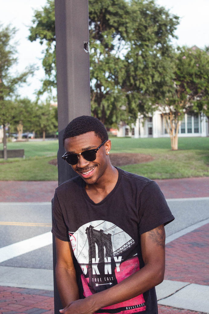Man Smiling While Leaning Metal Post